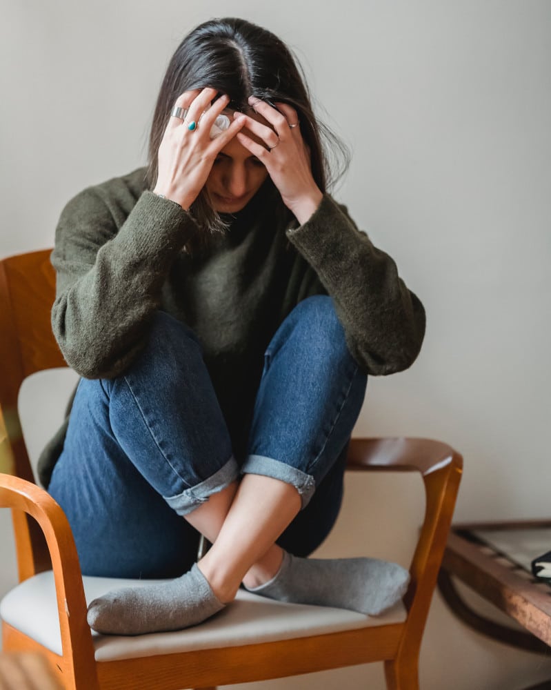 Woman sitting on chair, stressed.