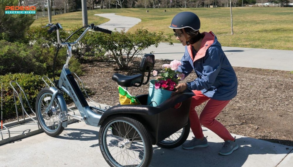 Cyclist loading flowers in the back of her electric tricycle.