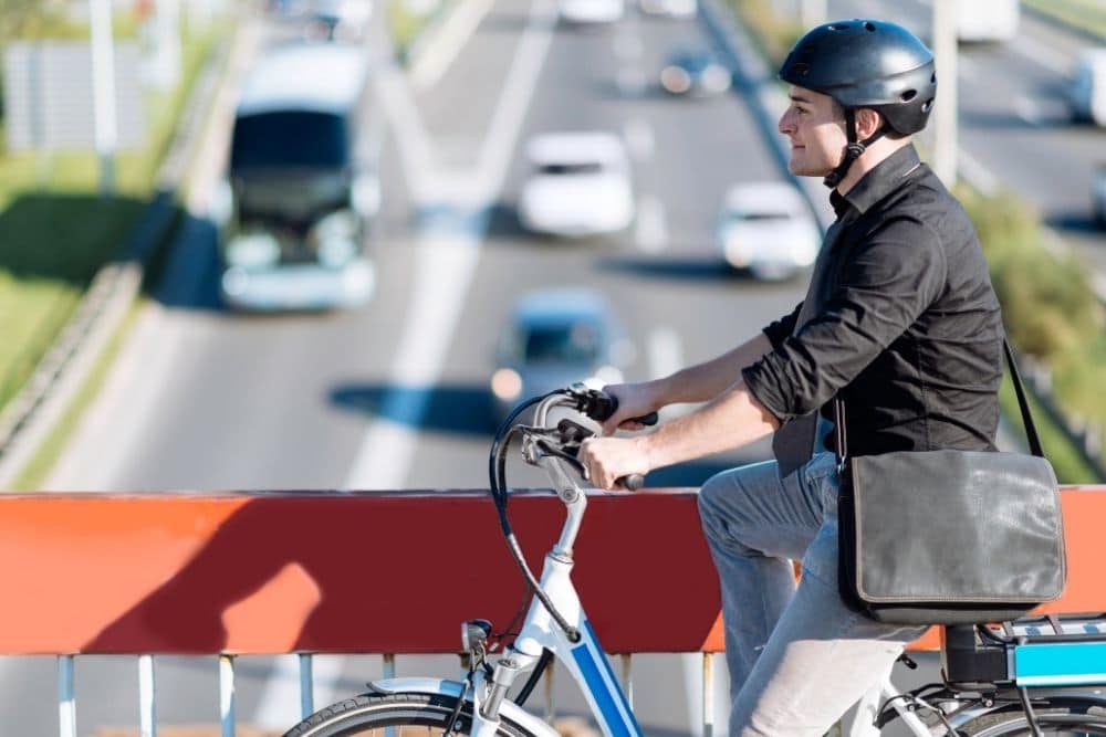 ebike rider over bridge looking at road traffic